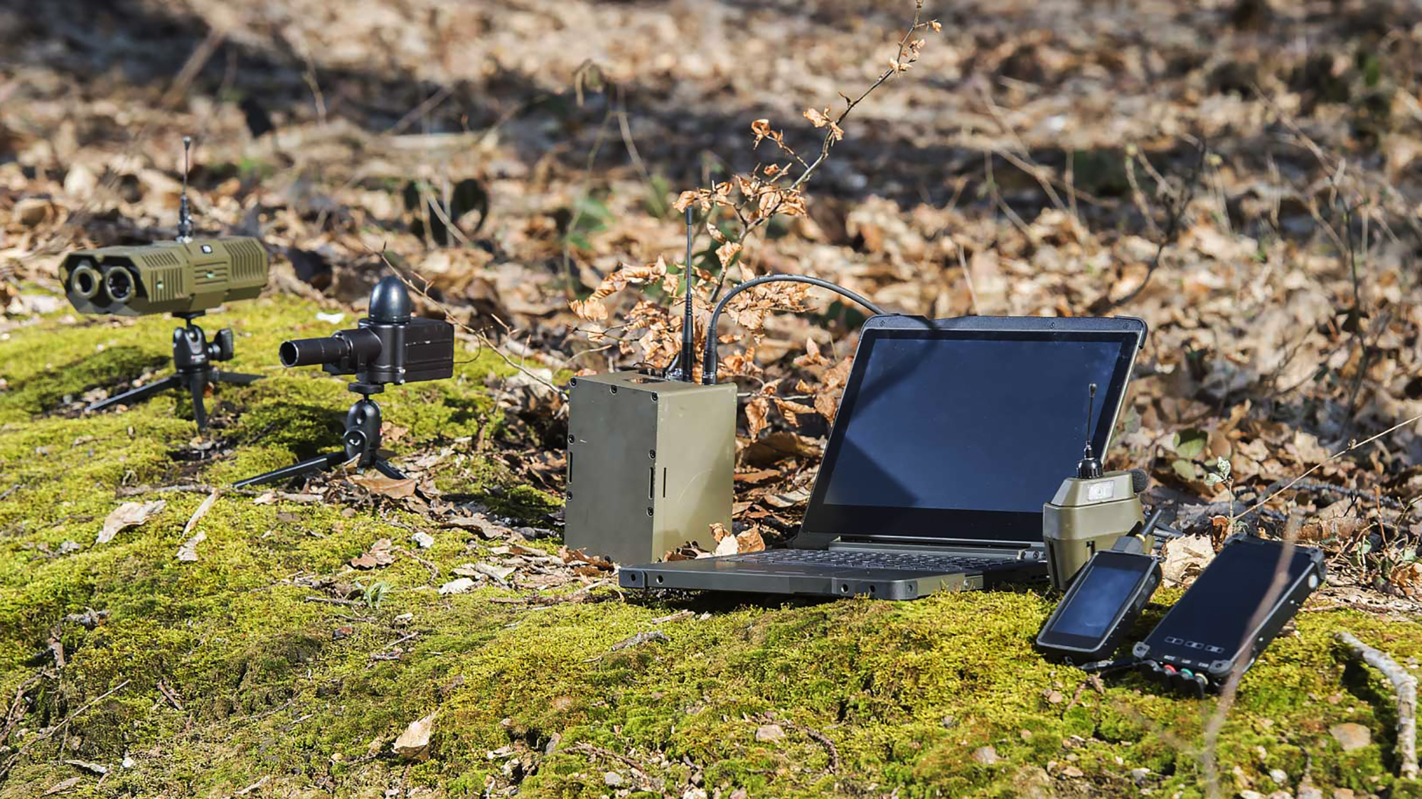 Sensorer, gateway, robust labtop och tablet på en mossig sten i skogen