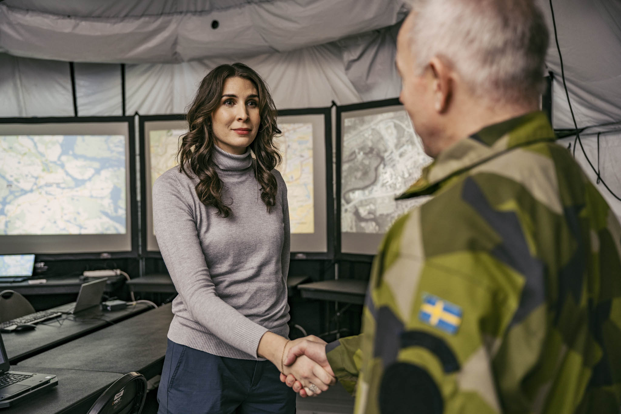 Medarbetare från FMV som skakar hand med en militär inuti ett tält