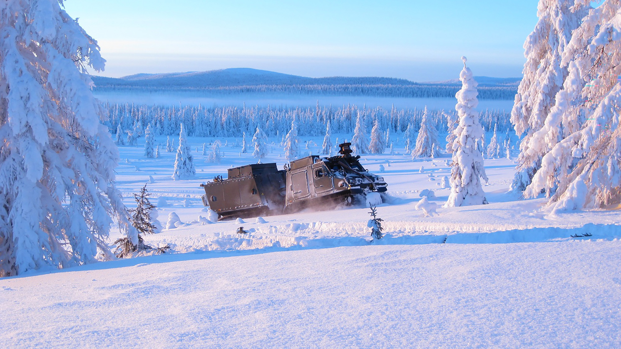 Bandvagn 410 kör i snötäckt landskap.