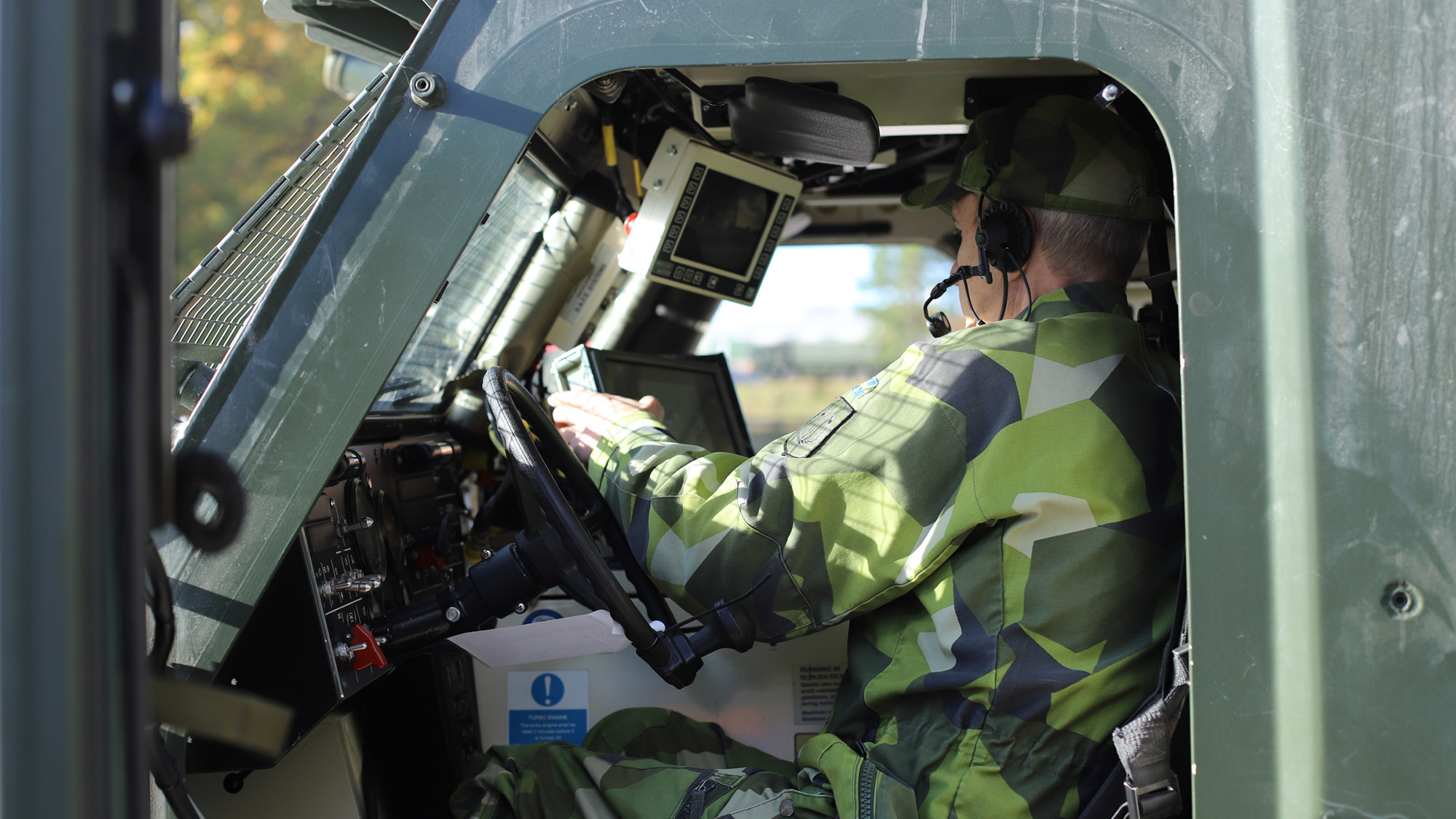 En soldat sitter i ett stridsfordon och tittar på en skärm som ingår i ledningsstödsystemet. 