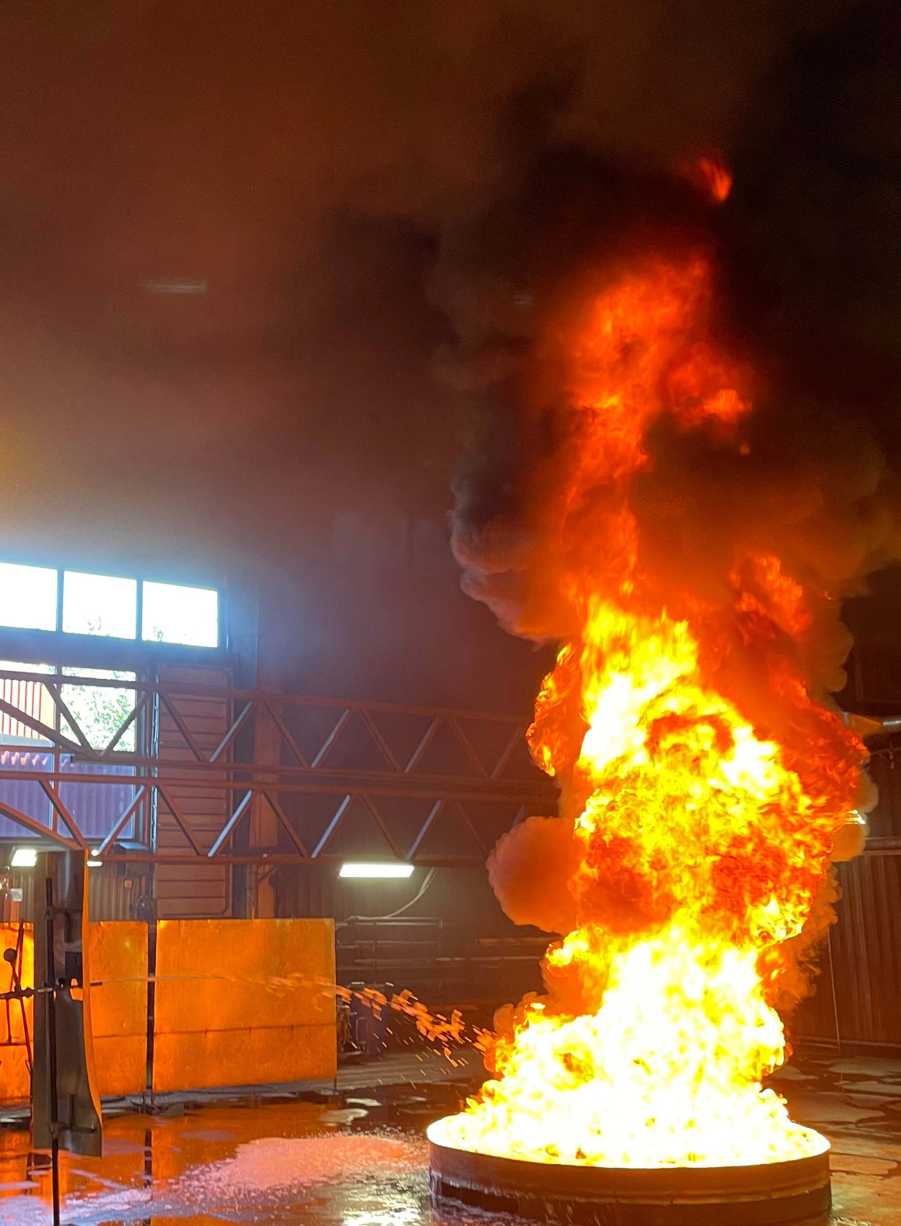 En stor, flammande, brand i ett runt kar, som står  i en lokal för testning. 