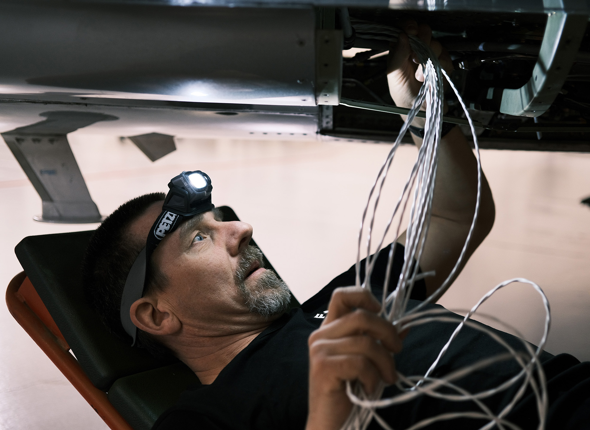 Eltekniker Anders Karlsson gör elektriska installationer i de flygplan och helikoptrar som används i tester vid provplatsen i Linköping. Arbetet sker ofta i trånga utrymmen. Foto: Karl-Kristofer Sjöström/FMV