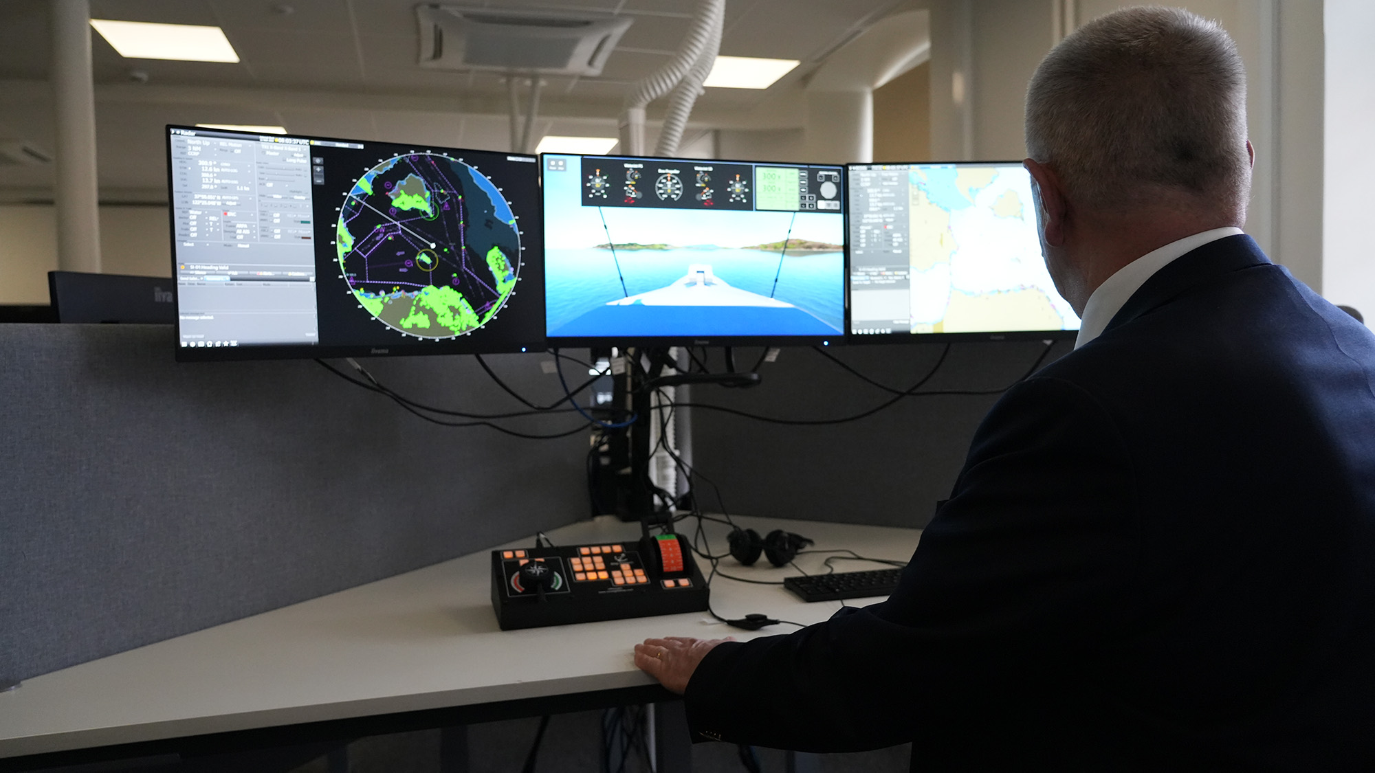 En man står framför skrivbord i klassrummet som tillhör simulatorn. 