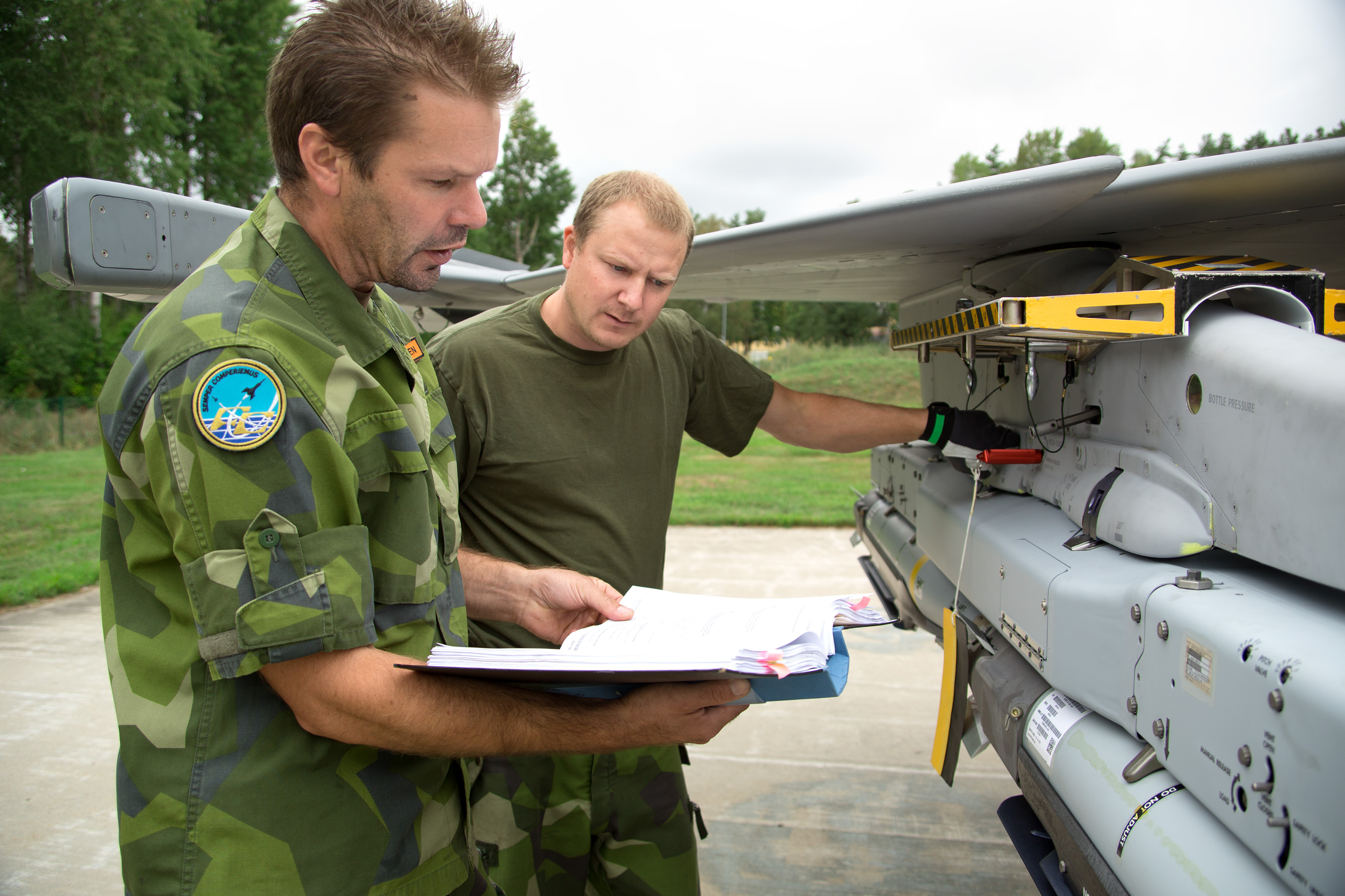 Två män vid JAS Gripen med en pärm