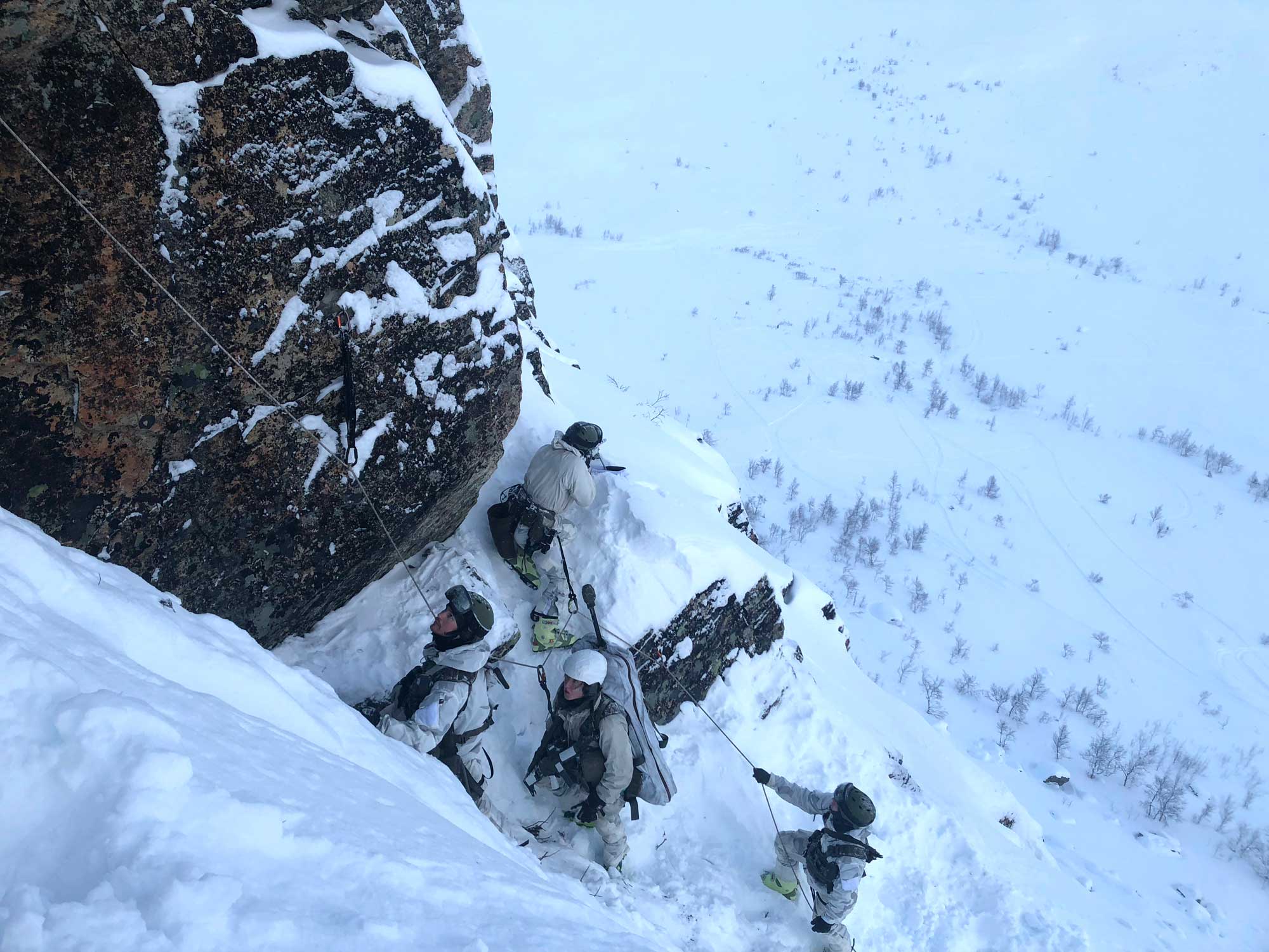 Fyra personer klättrar upp för ett snötäckt berg